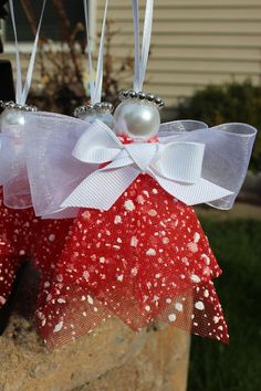 two red and white bows with pearls hanging from the side of a brick wall in front of a house