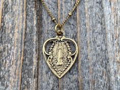 "Dainty and beautiful antique gold, antique replica, Our Lady of Lourdes heart shaped medal dangles on this antique gold plated 18\" satellite chain with a lobster clasp closure. This fine replica piece is cast in solid gold bronze using the lost wax method and produced in the U.S.A. The oxidation finishing process prevents tarnishing. Excessive skin oils may darken the backside of the medal so a polishing cloth is included. Since this is solid gold bronze, the medal will return to its original Virgin Mary Heart, Mary Heart, Opening An Etsy Shop, Lady Of Lourdes, Our Lady Of Lourdes, Necklace Antique, Blessed Virgin, Blessed Virgin Mary, Miraculous Medal