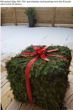 a wrapped christmas present sitting on top of a wooden table next to a planter