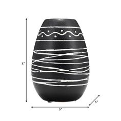 a black vase sitting on top of a white table next to a measuring tape and a ruler