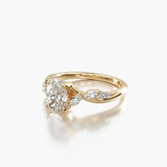 a yellow gold engagement ring with two pear shaped diamonds on the band and an oval diamond in the center