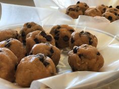 several chocolate chip cookies are on a white paper wrapper in a bowl, ready to be eaten