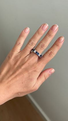 a woman's hand with a blue ring on her left thumb and two diamonds on the middle finger