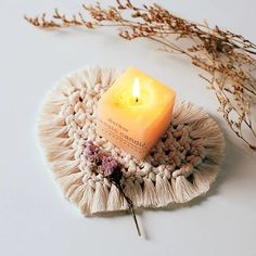 a lit candle sitting on top of a plate with dried flowers in the corner next to it