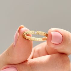 a woman's hand holding a gold ring with diamonds on the top and bottom