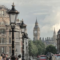 the big ben clock tower towering over the city of london as people walk down the street