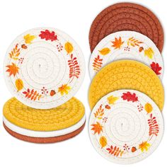 four plates with autumn leaves on them and one has an orange, yellow, and white design