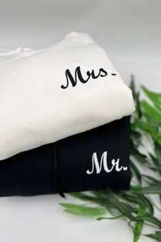 two black and white pillows sitting next to each other on top of a table with green plants