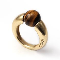 "Tiger Eye Geometric Cocktail Ring. FREE EXPRESS SHIPPING! Your new jewelry direct to your door! The Donut Tiger eye stone ring's benefits are beyond words: it is an incredible stone for achieving clarity. Traditionally carried as a talisman, this tiger ring is hand-forged for those who are glamorous and not afraid to show it. This sweet and colorful piece can also make the perfect birthday gift. If you love this piece with its inspiring tiger eye design, then you'll love our Blue round stone ri Modern Gold Stackable Gemstone Rings, Modern Gold Stackable Rings With Gemstones, Modern Stackable Gold Rings With Gemstones, Gold Crystal Sterling Silver Modern Ring, Modern Gold Crystal Ring In Sterling Silver, Modern Adjustable Gemstone Rings, Modern Yellow Gold Rings With Gemstone, Modern Yellow Gold Ring With Gemstone, Modernist Gold Jewelry With Gemstones