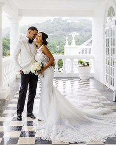 a bride and groom posing for a photo in front of a large white building with black and white checkered flooring