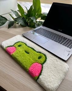 a laptop computer sitting on top of a wooden desk next to a rug with an animal face