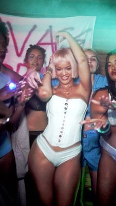 a woman in a white corset dancing at a party with other people behind her