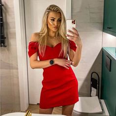 a woman in a red dress taking a selfie with her cell phone while standing in front of a mirror