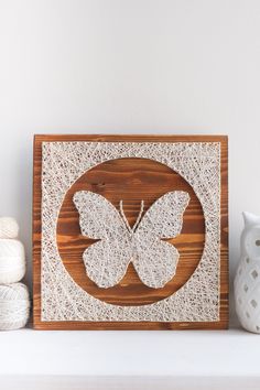 a white vase sitting on top of a table next to a wooden sign with a butterfly