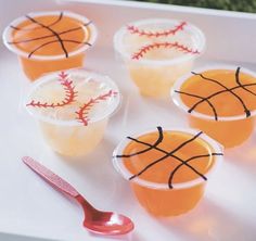 plastic cups filled with orange juice and decorated with baseballs on the side, sitting on a white tray