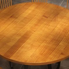 a round wooden table with four chairs around it and one chair on the other side