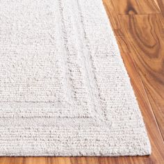 a white rug is on the floor with wooden floors and wood planks in the background