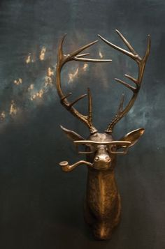 a metal deer head with glasses on it's face, against a dark background