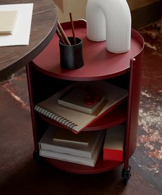 a red table with books and a vase on it