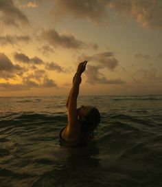 a woman in the water reaching up to catch a frisbee with her hand