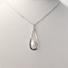 This hammered sterling silver pendant is just under 1 1/2" long and 1/2" wide. It features a teardrop shaped Pearl that is a little over 1/4" long. The pendant is on a .85 mm sterling silver box chain. The simple drop shape is elegant and beautiful.The necklace will be shipped in a decorative cardboard jewelry box filled with an anti tarnish cotton. Sterling silver is a metal that can tarnish, storing it in the box in which it is shipped will help prevent tarnishing. The piece can be cleaned wit Classic Silver Teardrop Pendant, White Drop Necklace For Anniversary, Elegant Teardrop Drop Necklace Nickel Free, Elegant Teardrop Nickel Free Drop Necklace, Elegant Teardrop Nickel-free Drop Necklace, Silver Long Drop Necklace With Pearl, White Gold Teardrop Pendant With Pearl Drop, Elegant Nickel-free Drop Necklace, Elegant Handmade Teardrop Drop Necklace