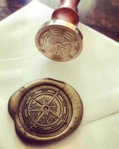 an old wax seal and stamp sitting on top of a piece of white paper next to each other