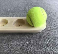 a tennis ball sitting on top of a wooden racket with two holes in it