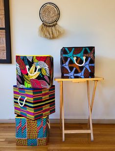 two colorful boxes sitting next to each other on top of a wooden table in front of a white wall