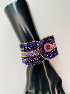 This bracelet is sized for a 7 3/4 inch wrist. It has a Czech button for the closure. The color palette is Purple and gold.   I have stitched this bracelet with strong Fireline thread, which is made to last with proper care of the bracelet. The width of this bracelet is 1 3/4 inches wide. Quality leather frames the cuff. Quality Japanese seed beads were used in this design. Adjustable Jubilee Cuff Bracelet With Round Beads, Adjustable Beaded Cuff Bracelet Bangle, Adjustable Multicolor Jubilee Cuff Bracelet, Adjustable Beaded Cuff Bangle, Adjustable Gold Beaded Wristband, Adjustable Beaded Wristlet, Beaded Cuff Jewelry Gift, Unique Adjustable Bracelet Wristlet, Handmade Adjustable Purple Bracelet