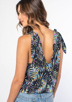 [Color: Black/Blue] A woman wearing a black sleeveless tank top with a blue tropical palm print and a tie shoulder accent. V-neck Tie Back Tank Top For Beach, Beachwear V-neck Tops With Tropical Print, V-neck Floral Print Tank Top For Beach, Floral Print V-neck Tank Top For Beach, V-neck Tank Top With Tie Back For Beach, Black Palm Tree Print Top For Beach, Vacation V-neck Tank Top With Tie Back, Printed Sleeveless Top For Vacation, Black Palm Tree Print Beach Top