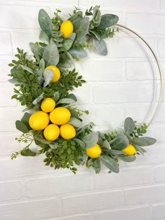 a wreath with lemons and greenery hanging on a brick wall