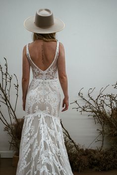 the back of a woman wearing a white dress and hat