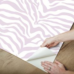 a woman is making a zebra print wallpaper with her hands on top of it