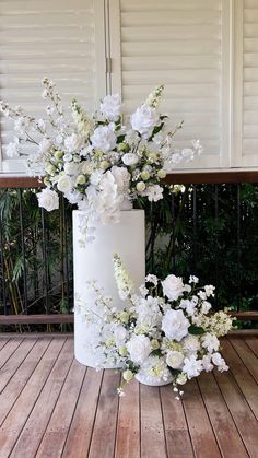 a white vase filled with flowers on top of a wooden floor