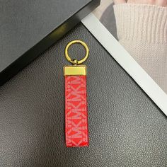 a red keychain sitting on top of a black leather table next to a photo