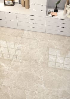 a bathroom with white cabinets and marble flooring