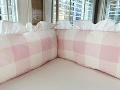 two pink and white pillows sitting on top of a bed next to a large window