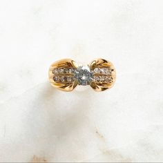 a yellow gold ring with two diamonds on the top and bottom, sitting on a white marble surface