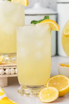 two glasses filled with lemonade and garnished with mint, sitting on a counter