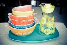 a stack of colorful dishes sitting on top of a blue tray next to a glass pitcher