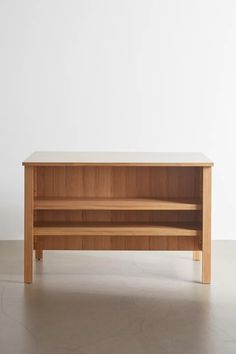 a wooden shelf sitting on top of a cement floor next to a white wall in an empty room