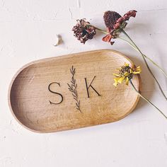 a wooden tray with flowers and the word sk on it