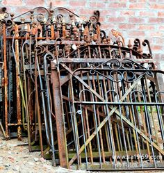 an old iron gate with many rusted metal bars on it next to a brick wall