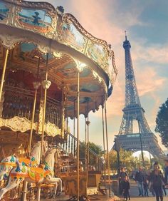 the eiffel tower is in the background as people ride on a merry go round