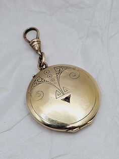 This is a fabulous antique locket that is perfect for your modern wardrobe! This large round gold-filled locket pendant features an extra special Art Deco inspired design on the front with a genuine garnet accent stone.  The reverse side has the original owner's monogram.  Inside is a portrait of a lovely young woman along with a hand sketched drawing of a cherub.  I do not know if anything is written on the reverse, as I did not want to disturb the tiny drawing.  Both gold filled frames and pic Luxury Antique Locket Jewelry, Antique Bronze Locket Necklace With Round Pendant, Antique Bronze Round Locket Necklace, Antique Bronze Round Pendant Locket Necklace, Antique Coin Pendant Jewelry, Victorian Medallion Locket Necklace Hallmarked, Round Locket Necklace Collectible, Elegant Compact Locket Jewelry, Victorian Hallmarked Round Pendant Locket Necklace