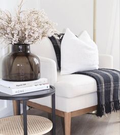 a vase with flowers sitting on top of a table next to a white couch and chair