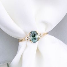 a ring with a blue stone on it sitting on top of a white cloth covered napkin