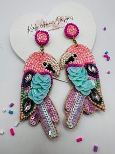 two pink and blue birds with beads on them