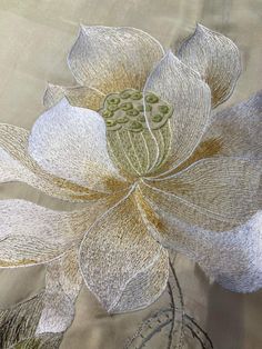 a close up view of a flower on a table cloth with embroidery work in the middle