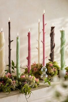 candles are lined up on a mantle with moss and flowers